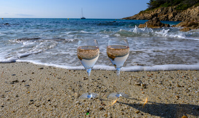 Summer time in Provence, two glasses of cold rose wine on sandy beach near Saint-Tropez in sunny day, Var department, France