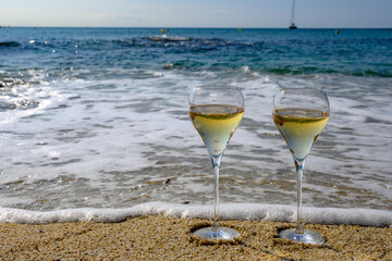 Summer time in Provence, two glasses of cold champagne cremant sparkling wine on sandy beach near Saint-Tropez in sunny day, Var department, France