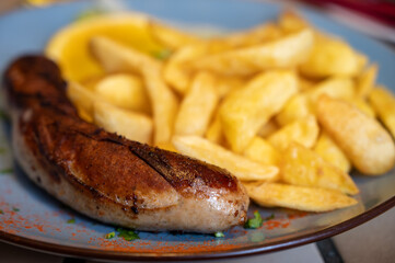 Fried fries potatoes with grilled meat German sausage served in old restaurant in Germany