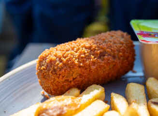 Dutch fast food, deep fried croquettes filled with ground beef meat and french fried potatoes chips served with green salad, close up
