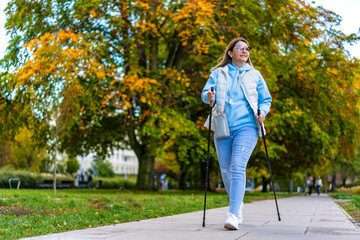 Fototapeta premium Nordic walking - mid-adult woman exercising in city park 