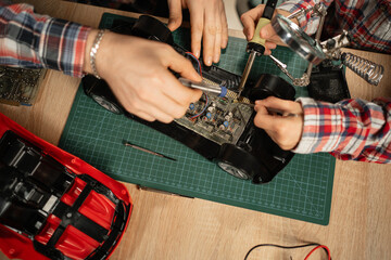 Close-up of father teaching his son for soldering remote controlled car at home, fixing broken toy.