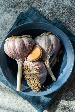 Overhead view of fresh garlic bulbs and garlic cloves in a bowl with a napkin