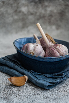Close-up of fresh garlic bulbs and garlic cloves in a bowl with a napkin