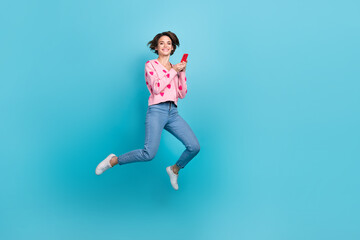Fototapeta na wymiar Full body photo of jumping overjoyed positive girl shopaholic enjoy order clothes online commerce advert isolated on blue color background