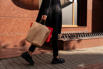 Close-up side view of a woman walking down the street carrying shopping bags, Belarus