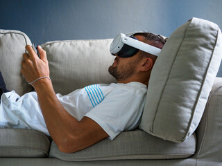 Man using virtual reality glasses, wearing new generation vr headset on sofa.