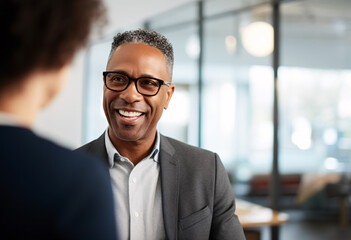 A 40s year old Afro male financial advisor in short grey hair with glasses counseling a woman in modern office setting natural lighting at day time
