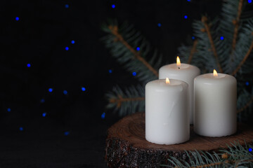buring candles on a textured wood stand on a black background.