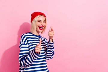 Photo of joking young girl wear red beanie headwear fingers directing you blinking eye advert...
