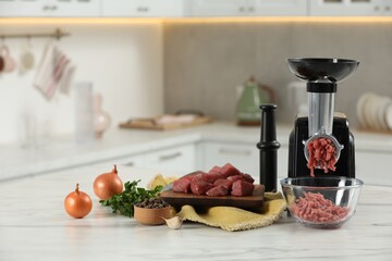 Electric meat grinder with beef mince and products on white table in kitchen