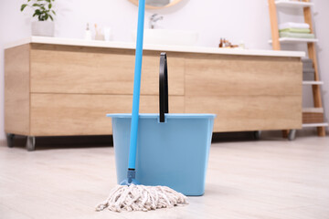 Mop and plastic bucket in bathroom. Cleaning floor - obrazy, fototapety, plakaty