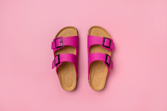 Trendy fashion footwear mockup. Leather pink magenta sandals birkenstocks on pink background top view flat lay. Unisex summer shoes, genuine leather flip flops with cork soles