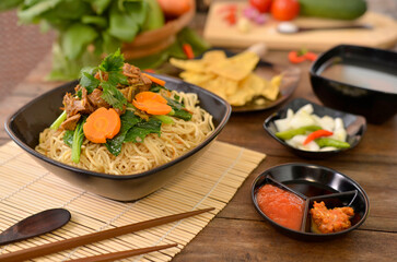 Mie Ayam, Indonesia's favourite street food Noodles topped with spiced chicken and green vegetables, served with gravy, tomato sauce, sambal and dumplings.