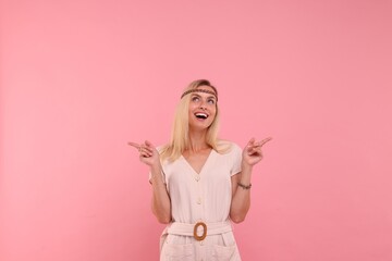 Portrait of happy hippie woman pointing at something on pink background