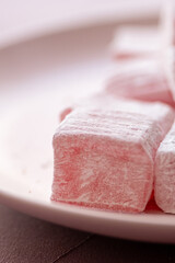 Pink Turkish delights with roses on a pink plate
