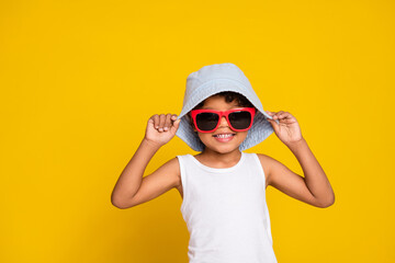 Full length photo of cheerful funky little boy dressed white shirt dark eyewear headwear empty space isolated yellow color background - obrazy, fototapety, plakaty