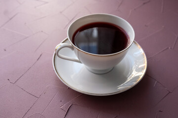 red colored tea in porcelain cup on pink background
