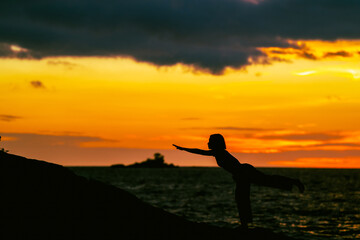 silhouette of a woman doing yoga on sunset