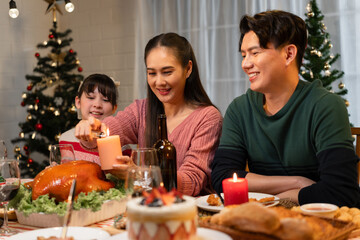Happy Asian family mother, father and daughter having dinner celebrating Christmas at home	