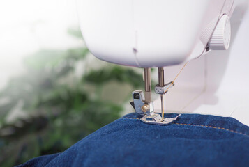 Close up sewing machine sew seam of blue denim jean.