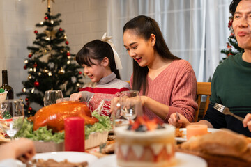 Happy Asian family mother, father and daughter having dinner celebrating Christmas at home	