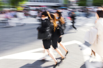 young Japanese women crossing the famous Shibuya Crossing in Tokyo, Japan