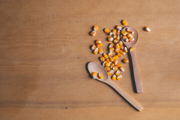 Top view corn seeds with wood spoon on the wooden background,