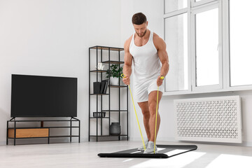 Fototapeta na wymiar Muscular man doing exercise with elastic resistance band on mat at home