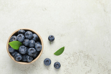 Tasty fresh blueberries in bowl on light table, flat lay. Space for text