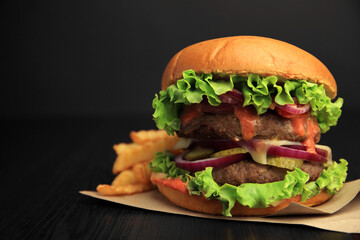 Tasty burger with vegetables, patties and lettuce served on wooden table, closeup. Space for text