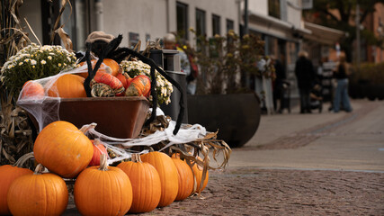 Pumpkins in old cart on shoppingstreet as outdoor halloween decoration, whit people shopping in the...