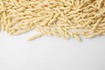 Uncooked trofie pasta on white background, flat lay. Space for text