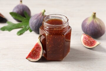 Jar of tasty sweet jam and fresh figs on white wooden table