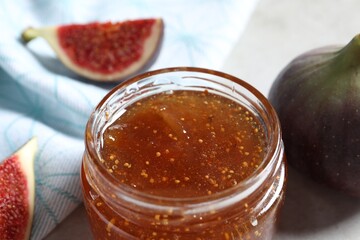 Jar of tasty sweet jam and fresh figs on table, closeup