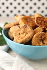 Bowl with tasty dried figs on white wooden table, closeup