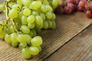 Different fresh ripe grapes on wooden table, closeup. Space for text