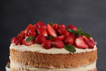 Tasty cake with fresh strawberries and mint on dark gray background, closeup