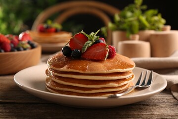 Tasty pancakes with fresh berries and mint on wooden table, closeup