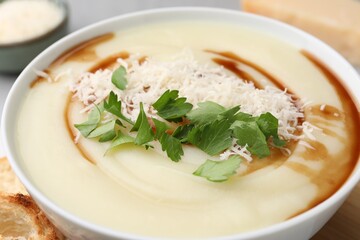 Delicious cream soup with parmesan cheese, soy sauce and parsley in bowl, closeup