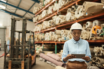 Fototapeta na wymiar Young African woman with a tablet working in a warehouse
