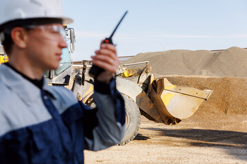 Concept open pit mine industry. Industrial worker of sand quarry use radio walkie talkie background...
