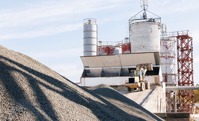 Yellow excavator truck transportation sand on industrial cement factory. Concrete plant industry concept
