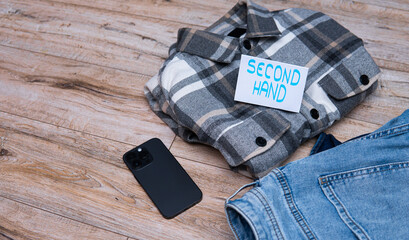 flannel shirt and jeans with the inscription second hand. flat lay photo showing the sale of used...