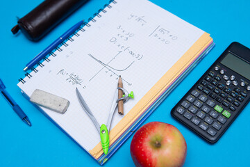 A close-up of a student solving math problems. Notebook with math tasks on a blue background. Solving math problems to practice