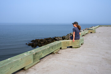 A woman looking at the sea from a wharf