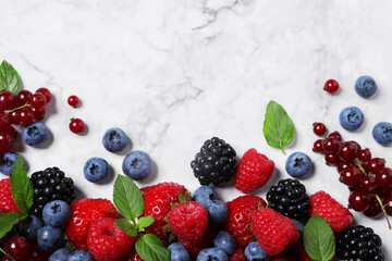 Many different fresh ripe berries on white marble table, flat lay. Space for text