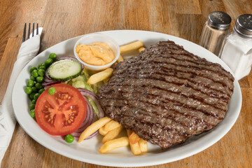 A grilled beefsteak with french fries on a plate.