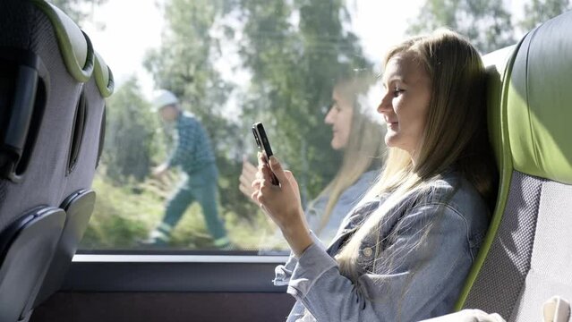 A woman tourist is traveling by a modern bus. Using a smartphone
