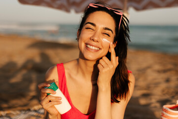 Woman using sunscreen cream. Beautiful woman with sun protection cream. Girl enjoy at the beach.